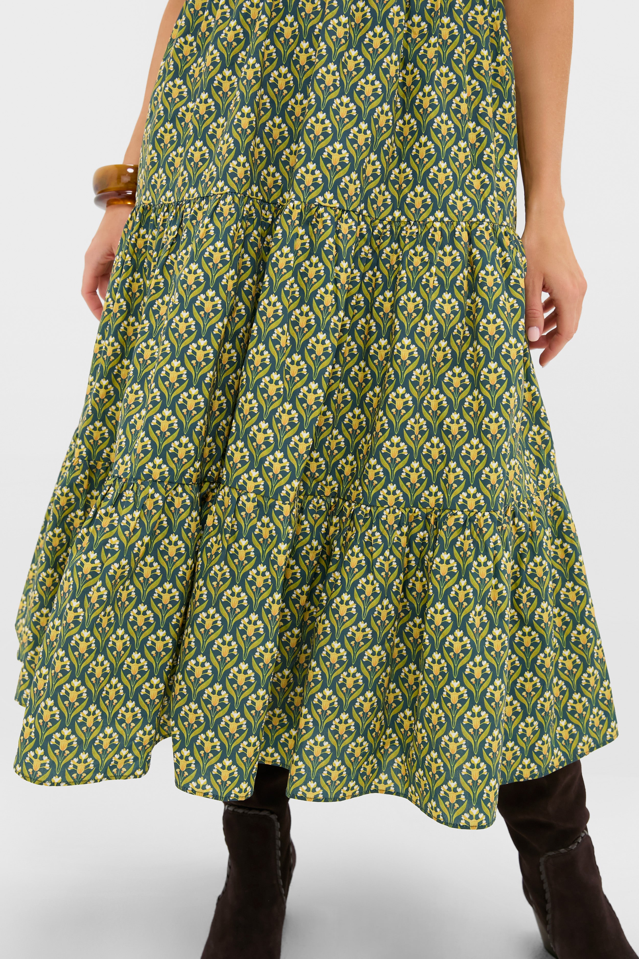 Forest Green Floral Bennett Maxi Dress showcasing a tiered midi skirt with yellow floral print, paired with dark boots and an amber bangle for a classic, effortless, high-end look.