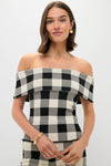 A woman exudes effortless style in a POSSE off-the-shoulder black and white heritage plaid top, paired with gold hoop earrings and bangles.