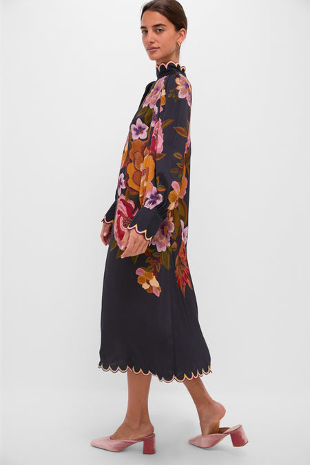 Woman modeling the Black Chenille Flowers Midi Dress with colorful floral print, scalloped trim, and blouson sleeves, styled with pink velvet mules for an effortless, high-end look.