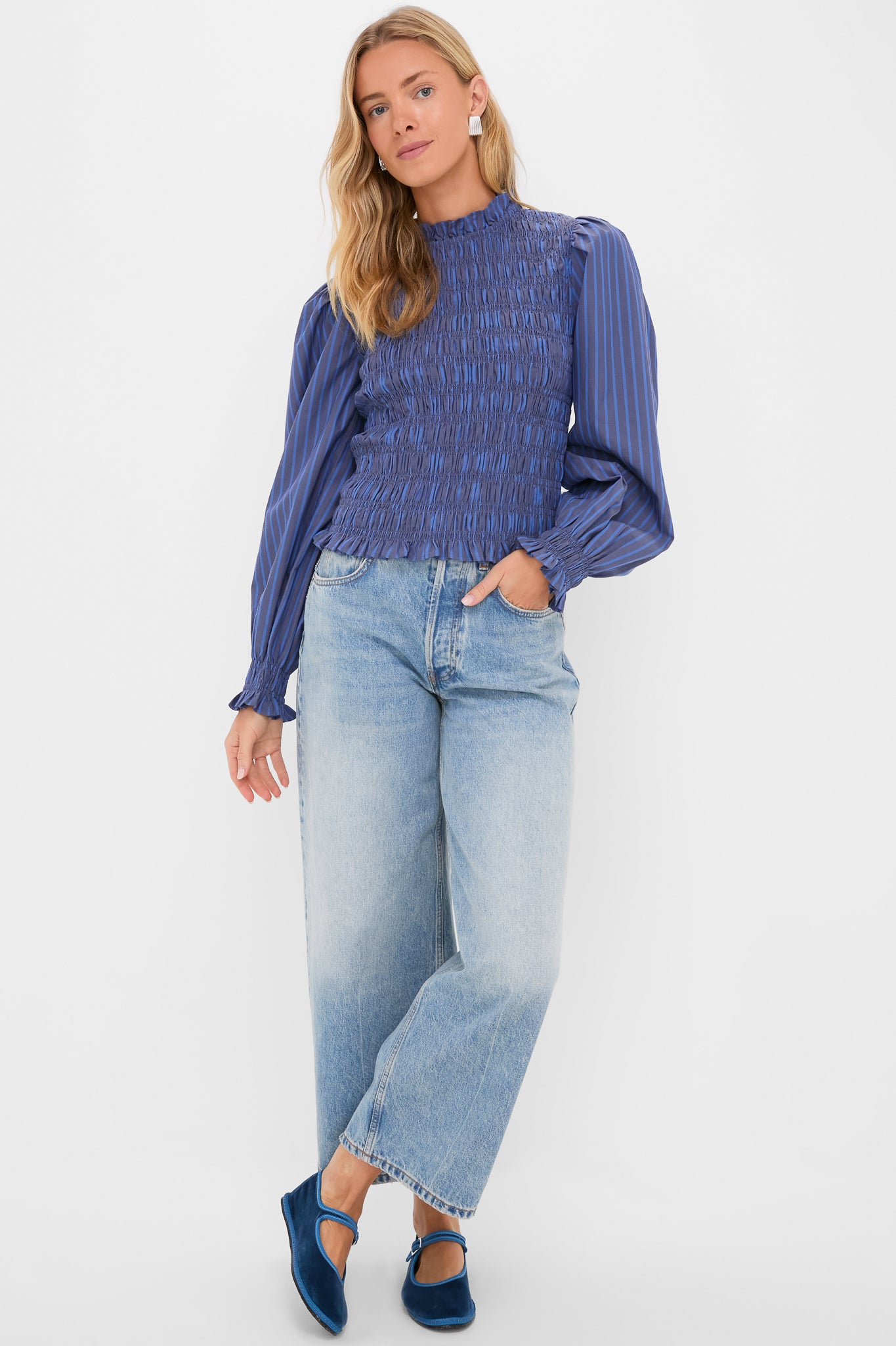 Person wearing the classic Morgan Blue Willow Top with ruffle trims and smocked bodice, paired with light-wash jeans and blue velvet Mary Jane flats, exuding effortless style.