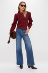 Model in a classic Merlot Embroidered Floral Frankie Sweater, effortlessly styled with wide-leg jeans and burgundy boots, embodying a fun, high-end, transitional look.