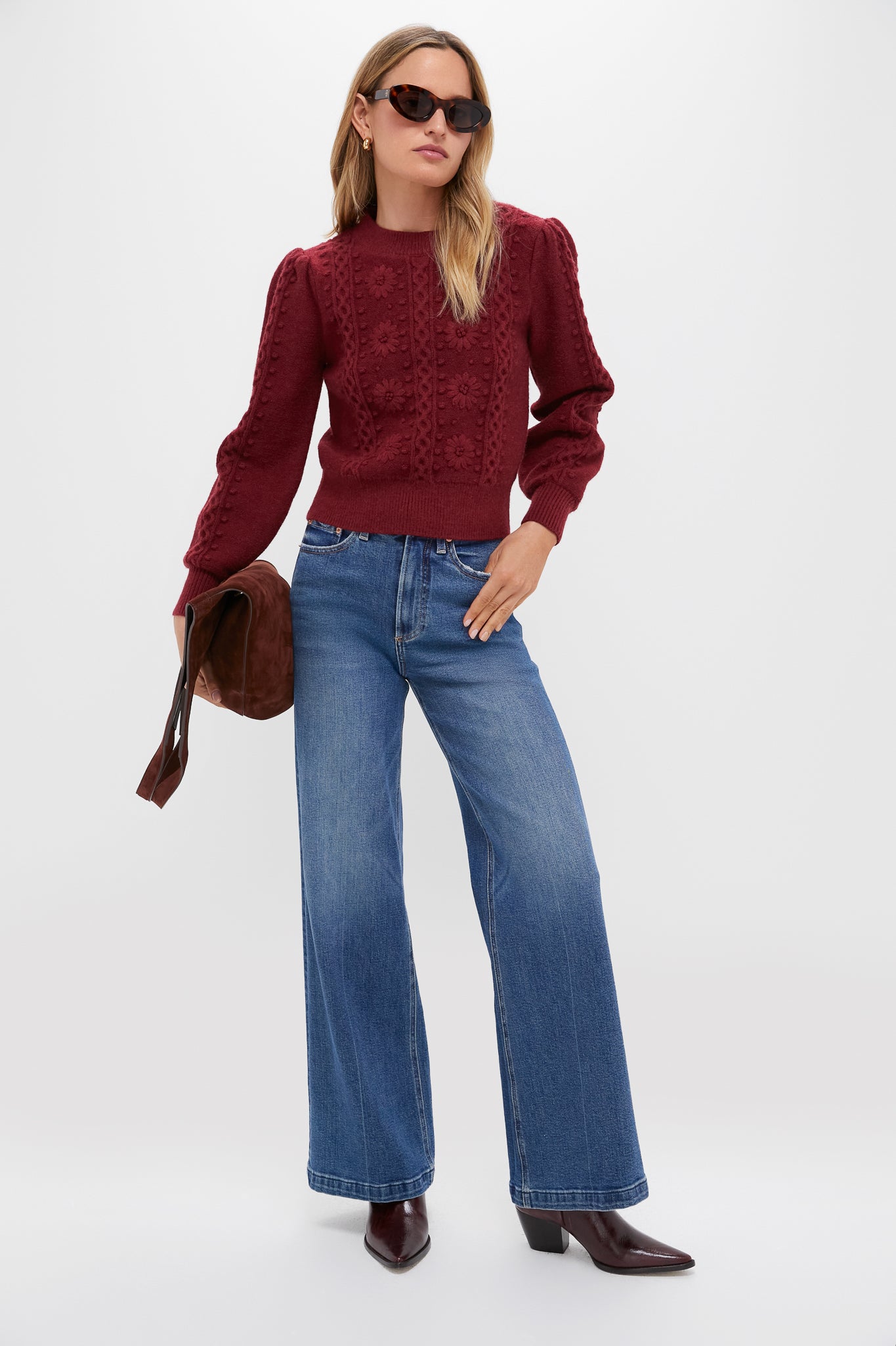 Model in a classic Merlot Embroidered Floral Frankie Sweater, effortlessly styled with wide-leg jeans and burgundy boots, embodying a fun, high-end, transitional look.