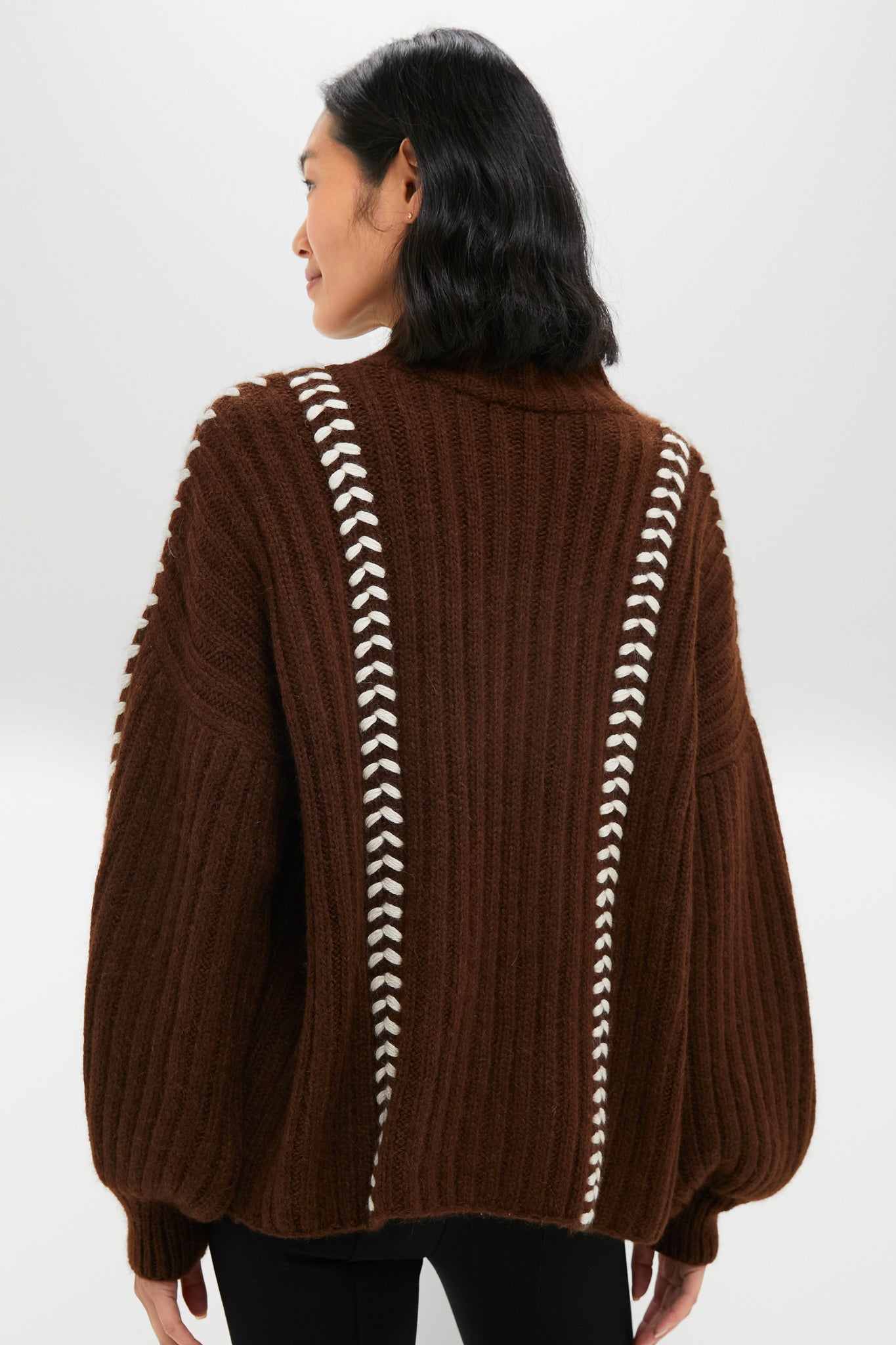 Classic Brown Mayu Sweater with contrasting white whip-stitch detailing, embodying effortless style and high-end craftsmanship, ideal for fun and chic winter layering.
