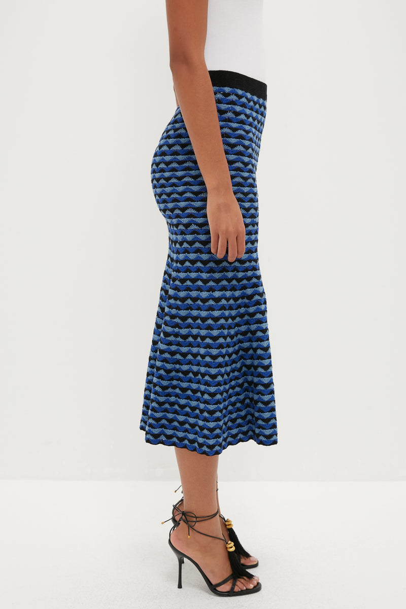 Model wearing the classic Blue and Black Profundo Midi Skirt, showcasing a fun, effortless wave pattern, paired with high-end black stiletto sandals.