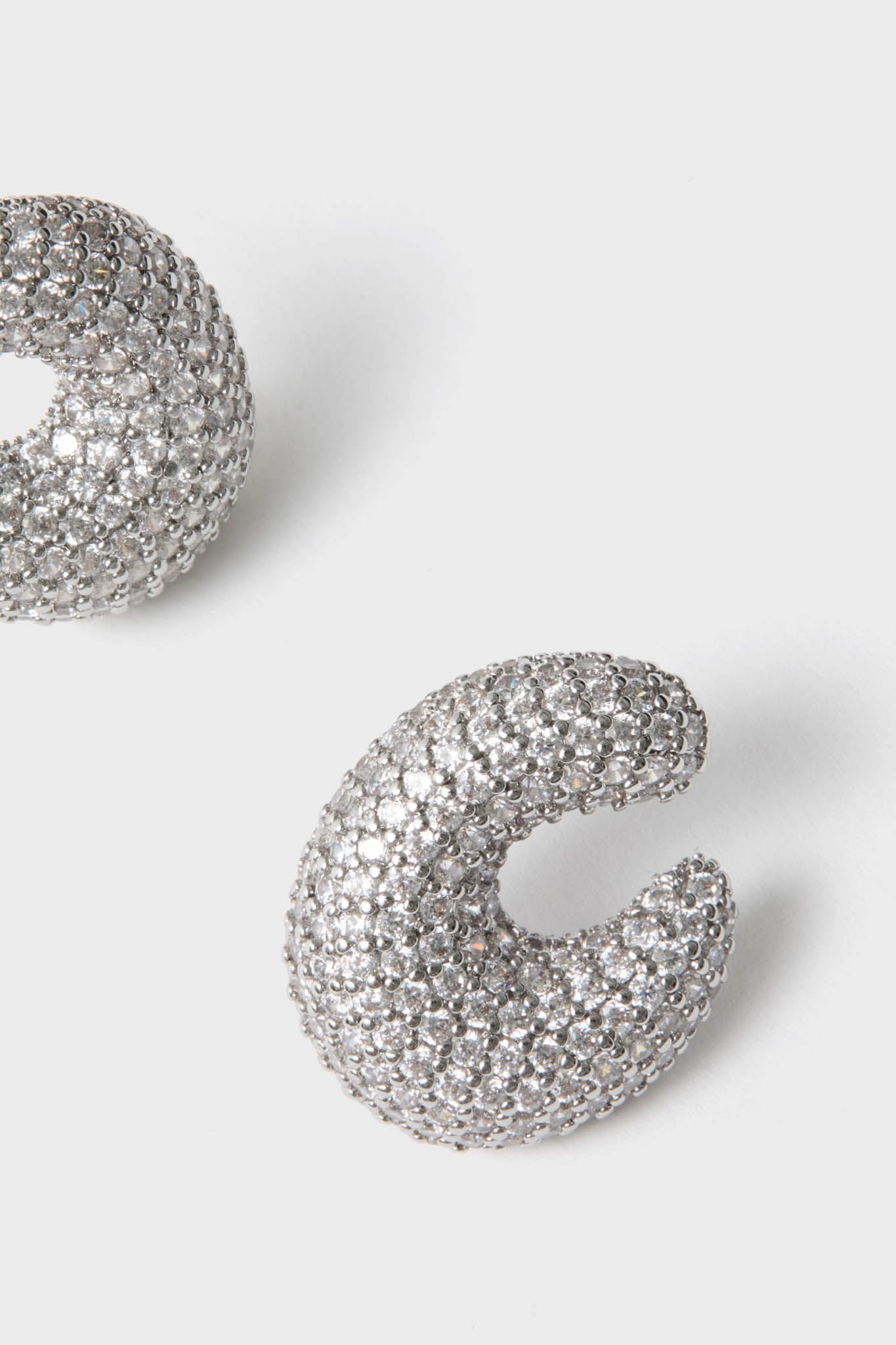 Silver Crystal Vera Earrings: Chunky, crescent-shaped hoops with pavé-set crystals, offering a classic, effortless sparkle for high-end style. Ideal for fun, glamorous occasions.