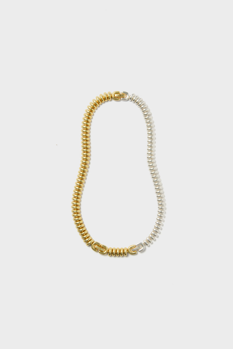 A coiled two-tone choker from Jenny Bird featuring one half in gold and the other in silver.