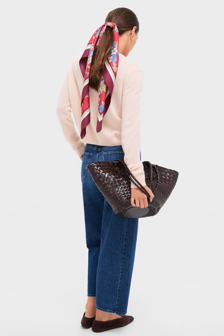 Woman with an effortlessly chic look, wearing the Scarlet Sakura Medium Silk Scarf tied in her hair, holding a classic woven leather tote, embodying a fun and high-end style.