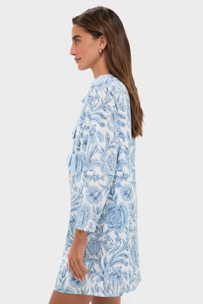 Young woman in profile wearing the Blue Chintz Clarice Bows Dress, a classic, high-end shift with blue floral print and playful front bow-tie detailing, embodying effortless and fun elegance.