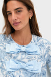 Young woman in Blue Chintz Clarice Bows Dress, featuring classic floral patterns and oversized satin bows, epitomizing effortless, fun, high-end style with a playful touch.