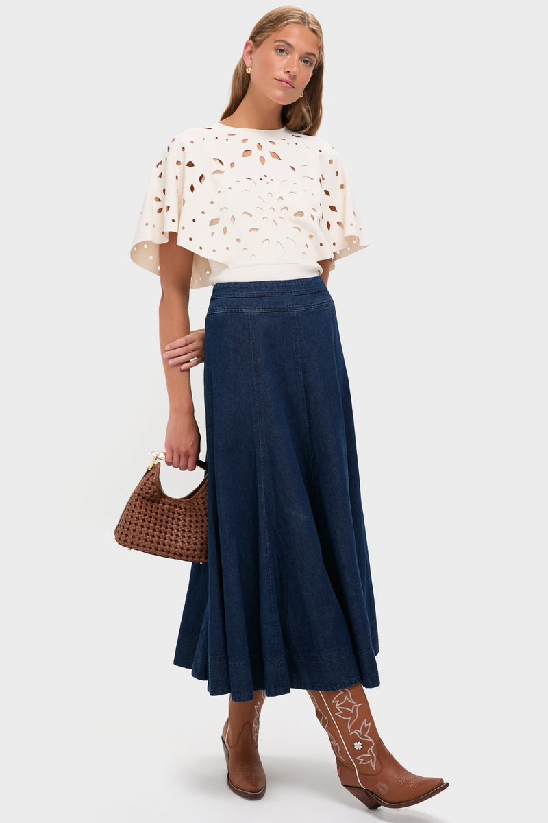 Model showcasing Sierra and White Honey Boots: classic cowboy boots with fun floral embroidery and effortless high-end design, paired with a chic cream top and denim skirt.