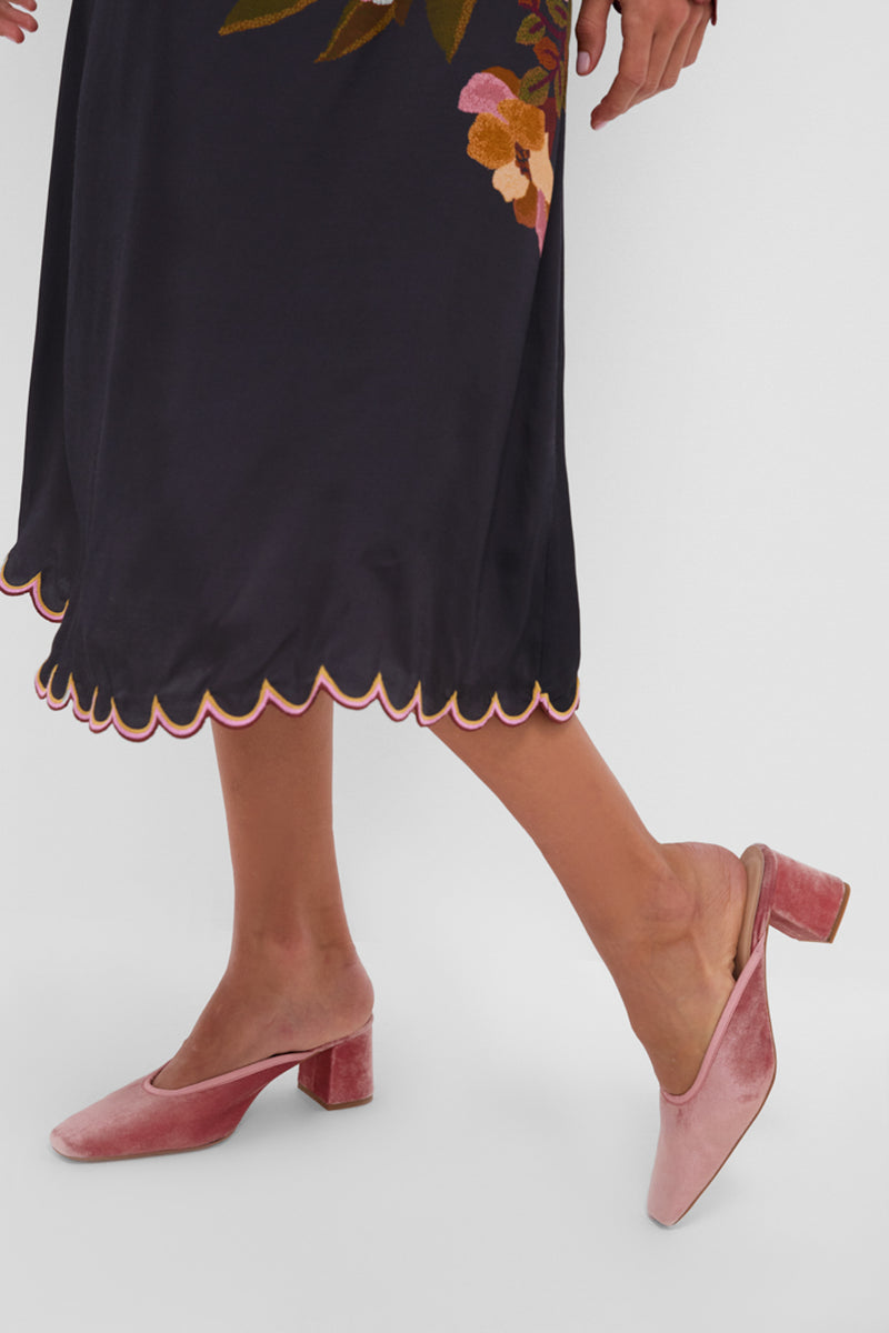 Close-up of a woman's legs wearing the Black Chenille Flowers Midi Dress with scalloped hem, paired with blush-pink velvet mules for a classic, effortless, high-end look.