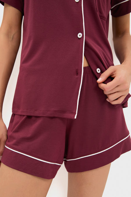 Woman in an Eberjey burgundy TENCEL Modal pajama set with white piping, featuring a short-sleeve button-up top and shorts—a stylish, sustainable loungewear choice for comfort.