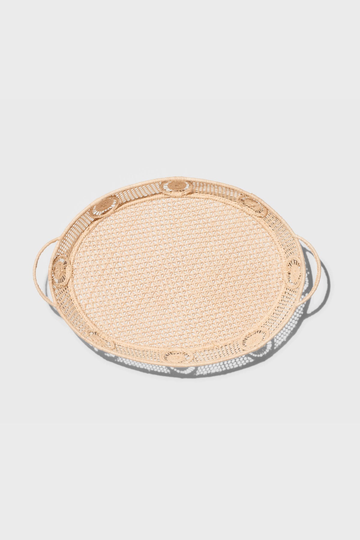 The AERIN round rattan tray features two side handles and raffia accents, adding a touch of coastal design.