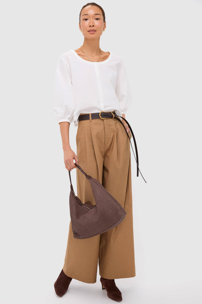 Model wearing Umber Slubby Cotton Atelier Pleated Pant 2, styled with a classic white blouse, dark belt, and accessories for an effortless, high-end, fun look.