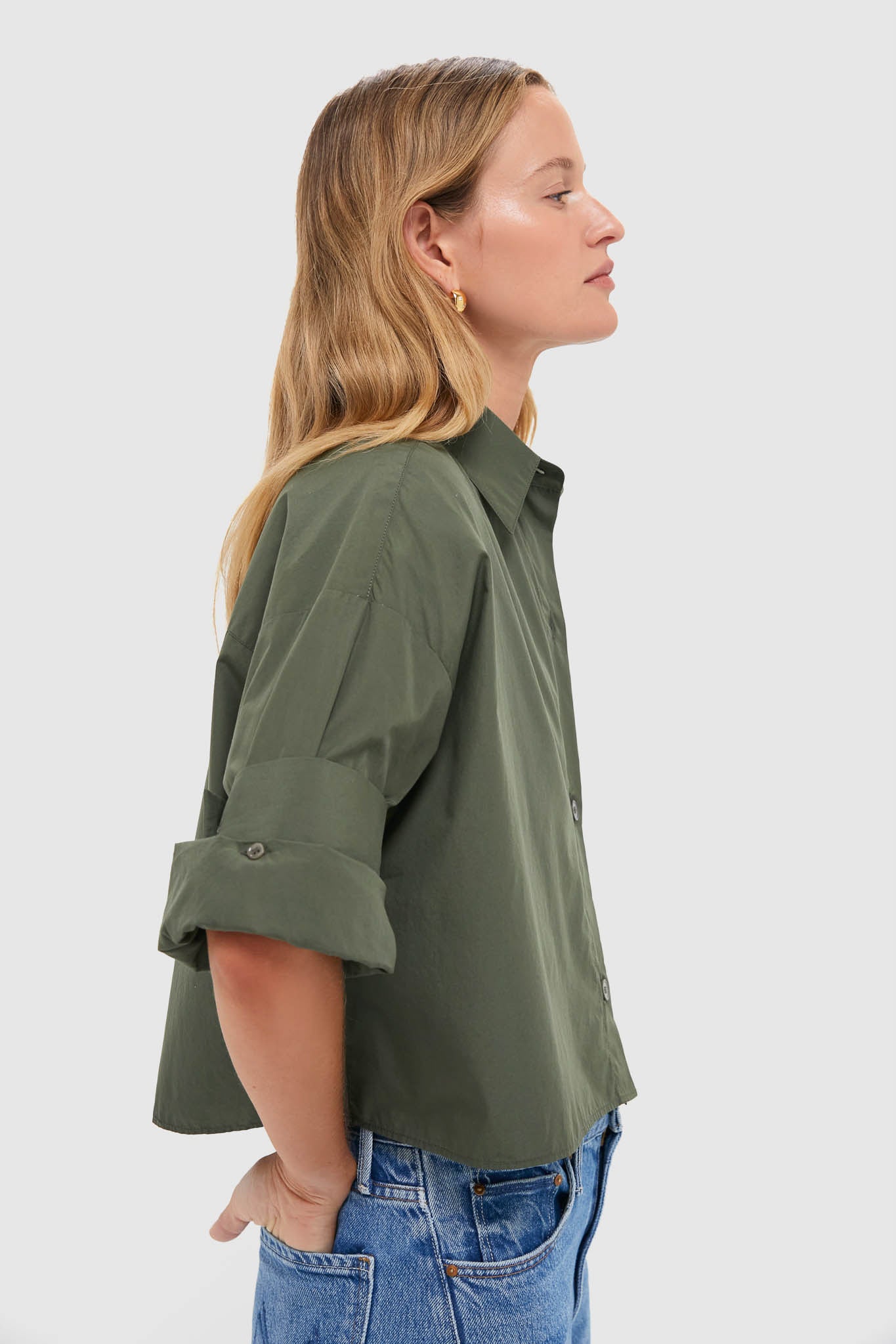 Side-profile of woman wearing the classic Duffle Bag Next Ex Shirt, showcasing its effortless, high-end style with a boxy, cropped silhouette and double roll cuffs.