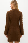 Back view of a model in a classic Coffee Cable Knit Lucia Mini Dress, showcasing long sleeves and a mock neck, paired with gold accessories for an effortless, high-end look.
