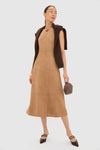 A woman in a Tuckernuck Beige Vegan Suede Dress with a column silhouette, a brown sweater over her shoulders, carrying a textured handbag, and wearing brown pointed-toe heels—a perfect fall wardrobe addition.