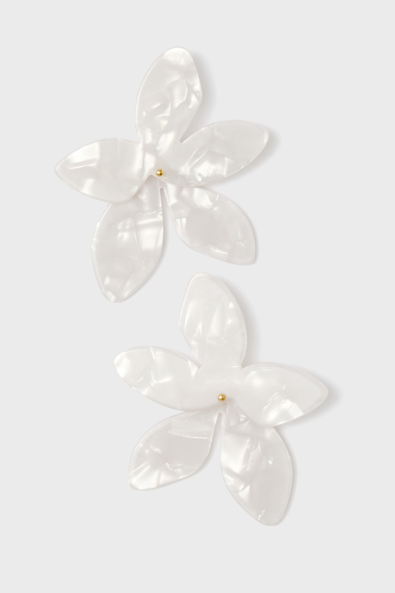A pair of white, translucent flower-shaped earrings with gold bead centers.