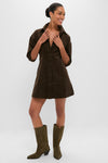 Model in Carob Luz Mini Dress, a classic corduroy shirt-dress with a fitted waist and flared skirt, styled effortlessly with cowboy boots for a fun, high-end look.