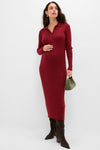 A woman wears a HATCH cotton rib knit long-sleeve burgundy maternity dress with a collared, buttoned neckline, paired with brown knee-high boots and a small green handbag.