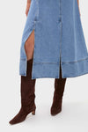 A person in a Hunter Bell blue denim midi dress with front slits, styled with knee-high dark brown suede boots.
