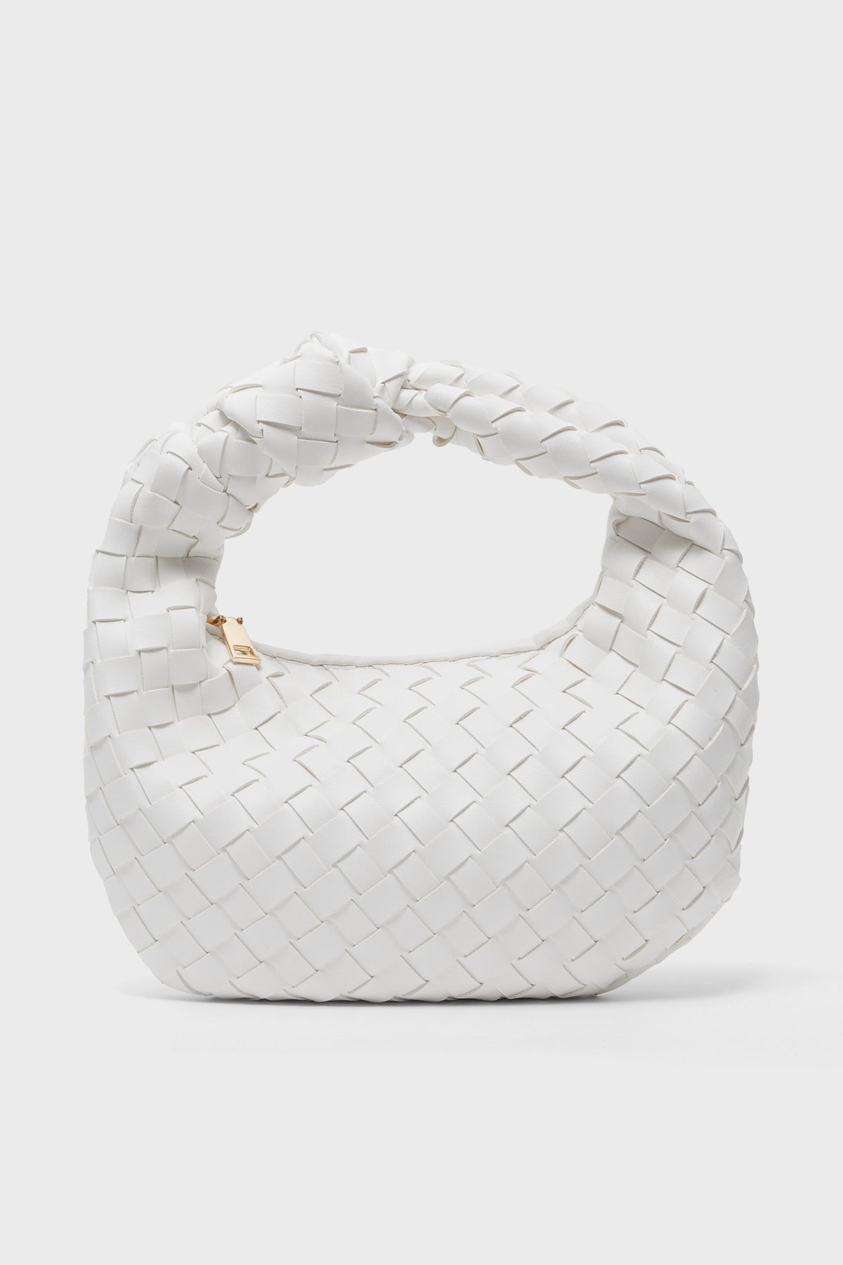 Urban Expressions presents a small white vegan handbag featuring a woven vegan leather texture and a twisted handle, displayed in an elegant, minimalist setting.