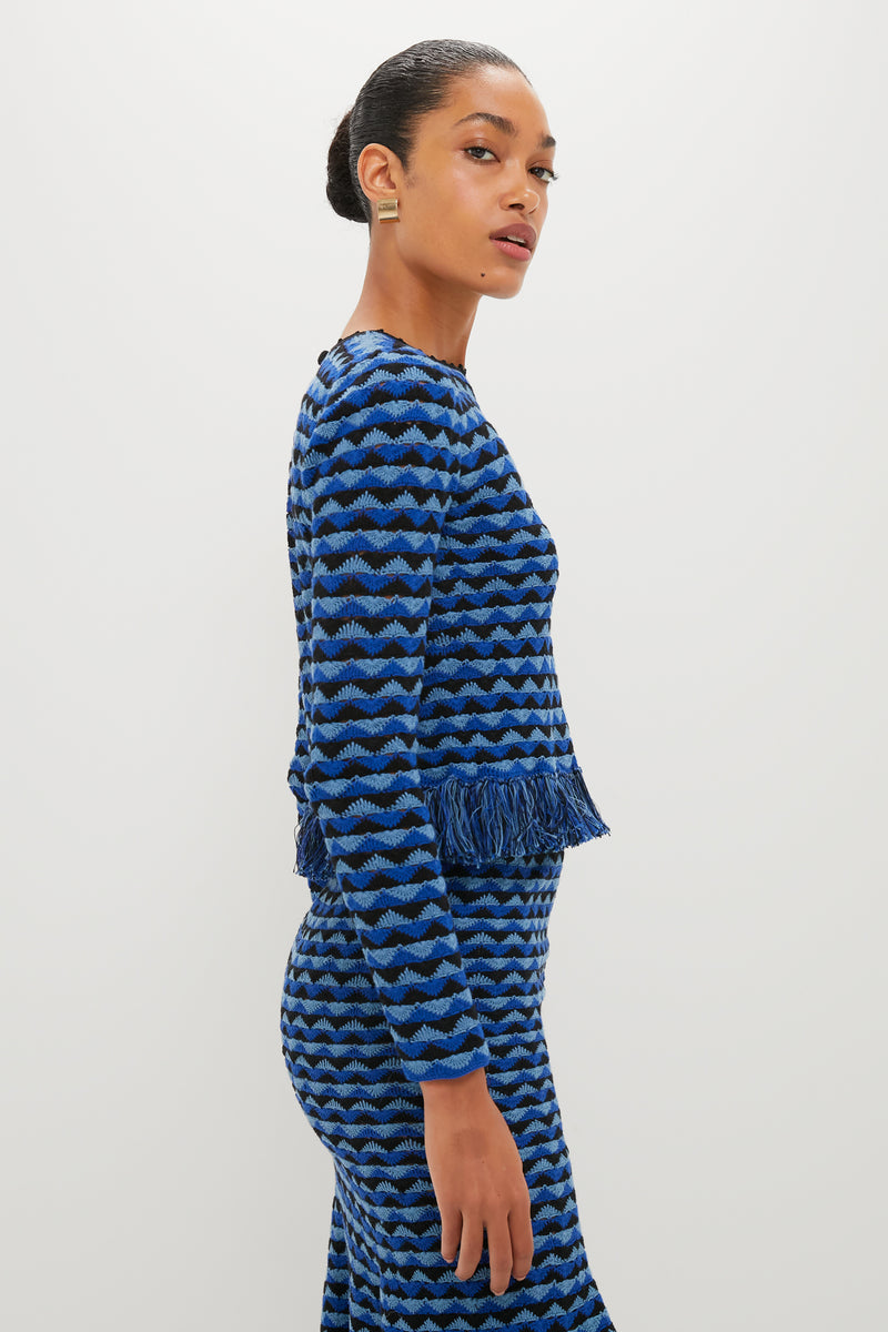 Model in a classic, high-end Blue and Black Profundo Long Sleeve Top with wave pattern and fringe, styled effortlessly with matching skirt for a fun, elegant look.