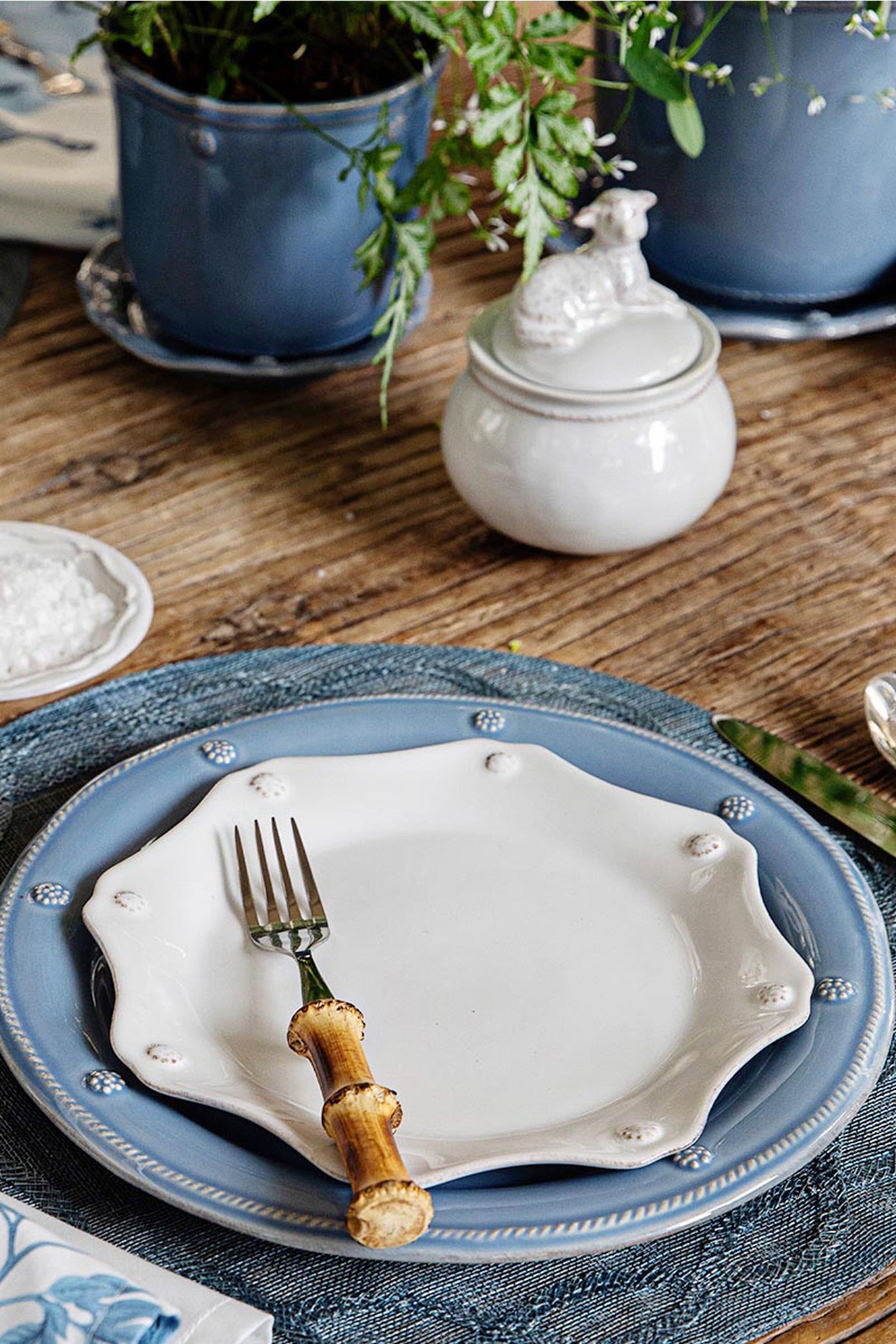 Classic Chambray Berry & Thread Dinner Plate on a rustic table, paired effortlessly with a bamboo-handled fork, embodies high-end, fun farmhouse elegance in a casually sophisticated setting.