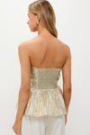 Back view of a woman in a classic Gold Plisse Iris Strapless Top with a smocked back and flouncy hem, styled with light trousers for an effortless, high-end look.