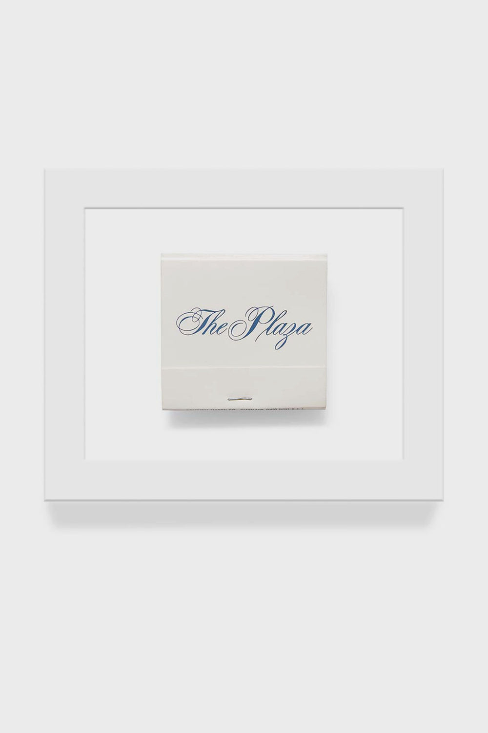 A framed matchbook print from Matchbook Diaries by Charles Ryan Clarke features The Plaza in blue script, captured with macro photography for striking detail.