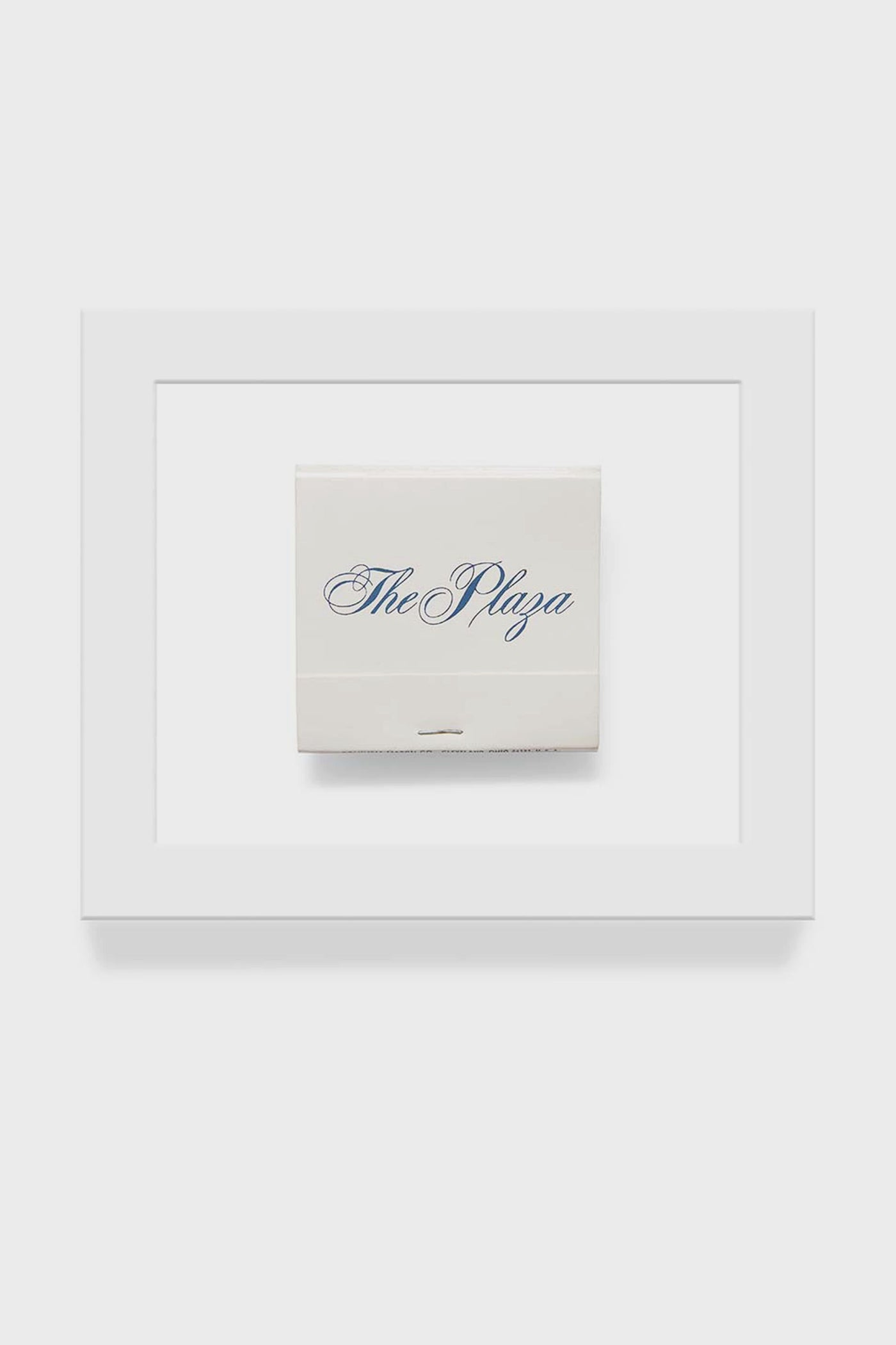 A framed matchbook print from Matchbook Diaries by Charles Ryan Clarke features The Plaza in blue script, captured with macro photography for striking detail.