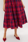 A person wearing a Hill House Home red and navy plaid A-line midi skirt with red pointed low-heeled shoes stands against a plain background.