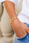 Classic and effortless, the Berry Clover Linear Bracelet in gold adorns a wrist, adding a touch of fun and high-end charm against casual denim.