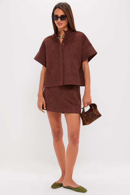 Model showcases the classic Ganache Vegan Suede Meg Mini Skirt, an effortless high-end piece paired with a matching top and fun accessories, embodying chic style.