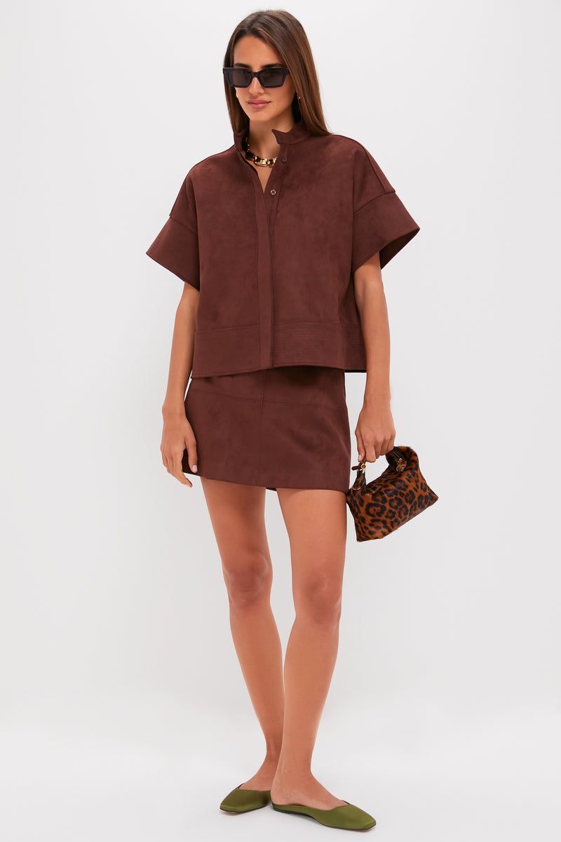 Model showcases the classic Ganache Vegan Suede Meg Mini Skirt, an effortless high-end piece paired with a matching top and fun accessories, embodying chic style.