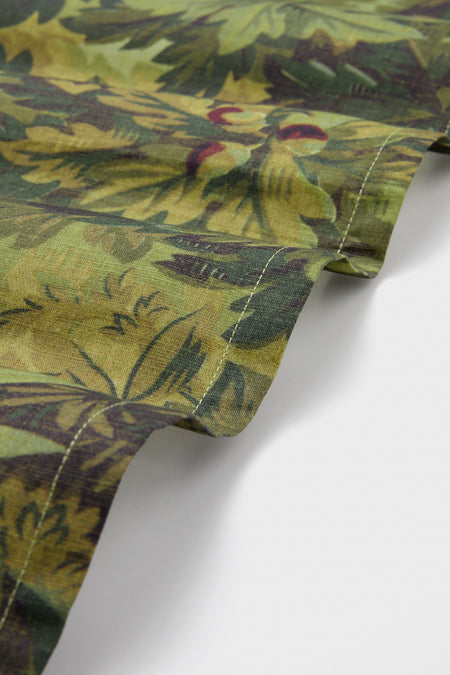 Close-up of a Tuckernuck Home cotton napkin from a set of 4, featuring a green and brown leafy pattern with detailed edge stitching, shown against a white background.
