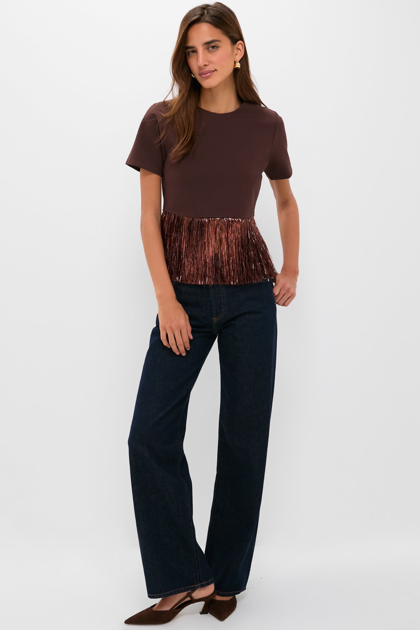 Woman models the Bronze Metallic Fringe Francie Short Sleeve Blouse, effortlessly combining classic and fun style with high-end, chic details, paired with dark indigo jeans.