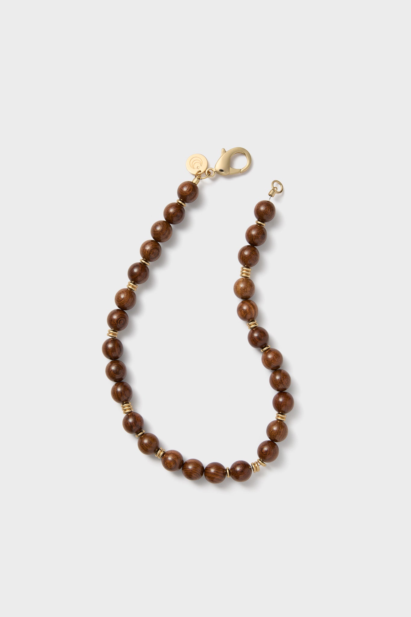A beaded bracelet by Jane Win featuring round brown wooden beads, gold spacer beads, a gold lobster clasp, and a small round gold charm—an elegant piece that complements any wood bead necklace.