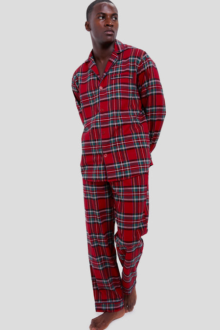 A person stands barefoot wearing a Petite Plume red plaid long-sleeve pajama set, inspired by luxury cotton sleepwear.