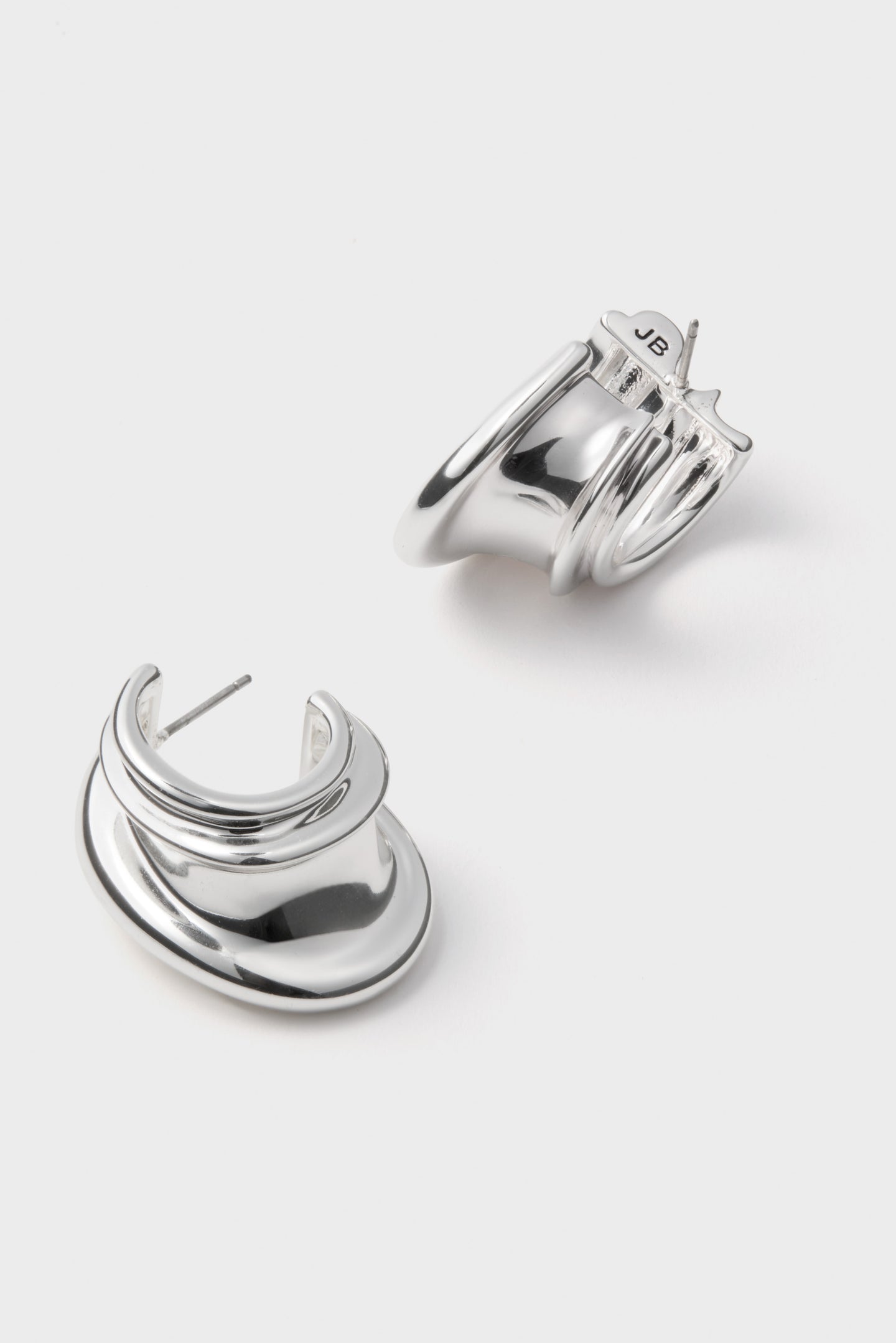 High Polish Silver Leona Hoops with wavy sculptural design, showcasing a classic, effortless style. Perfect for fun, high-end looks; features post back and “JB” hallmark.