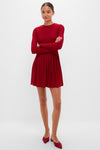Woman in Red Shimmer Pleated Bale Mini Dress with classic, effortless style; fitted bodice, pleated skirt, and matching red low-heeled mules for a fun, high-end look.