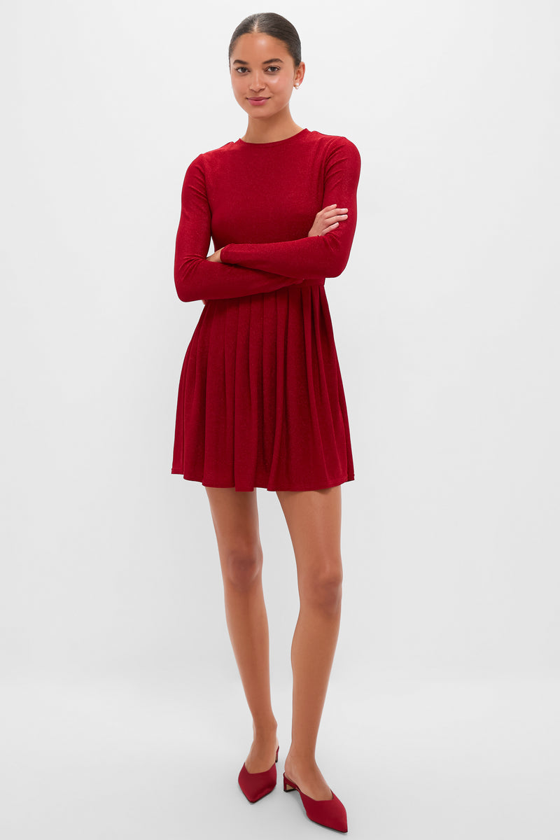 Woman in Red Shimmer Pleated Bale Mini Dress with classic, effortless style; fitted bodice, pleated skirt, and matching red low-heeled mules for a fun, high-end look.