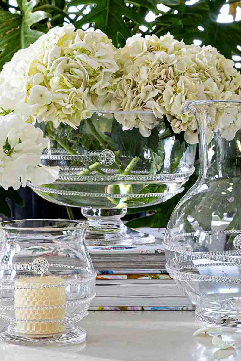 Classic and high-end, the Amalia 10 Footed Bowl holds elegant hydrangeas, complemented by glass vessels, showcasing an effortless and fun centerpiece.