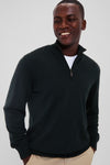 A man smiles while wearing a Barbour merino sweater with a Teflon-coated finish over a white shirt and beige pants.