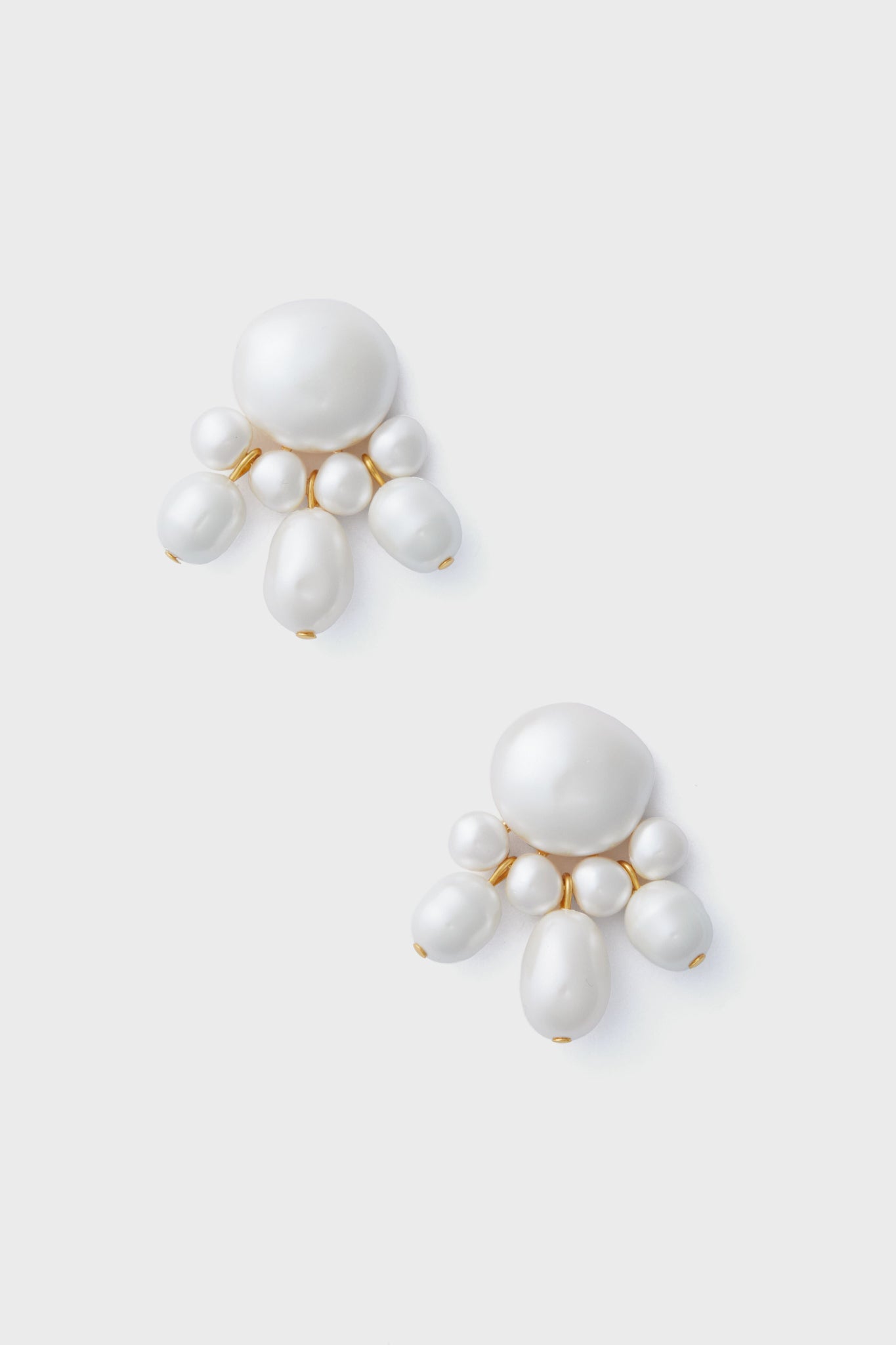 A pair of statement earrings from Tuckernuck Jewelry, in white with elegant gold-plated accents.