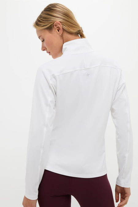Woman in a classic White Performance Jersey Carver Quarter Zip Tee, showcasing its effortless, high-end style with a mock-neck and long sleeves, perfect for fun, active pursuits.