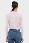 Woman in high-waisted jeans wearing the Blush Pink Gilberte Embroidered Cardigan, showcasing an effortless, fun look with classic cable-knit design embellished with sequins.