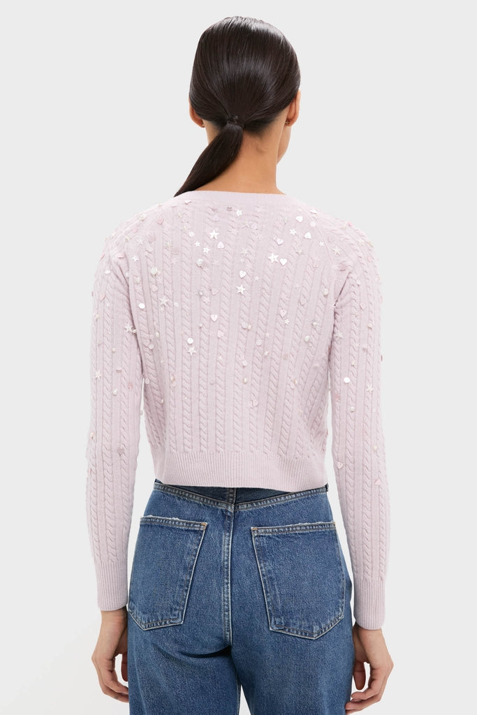 Woman in high-waisted jeans wearing the Blush Pink Gilberte Embroidered Cardigan, showcasing an effortless, fun look with classic cable-knit design embellished with sequins.