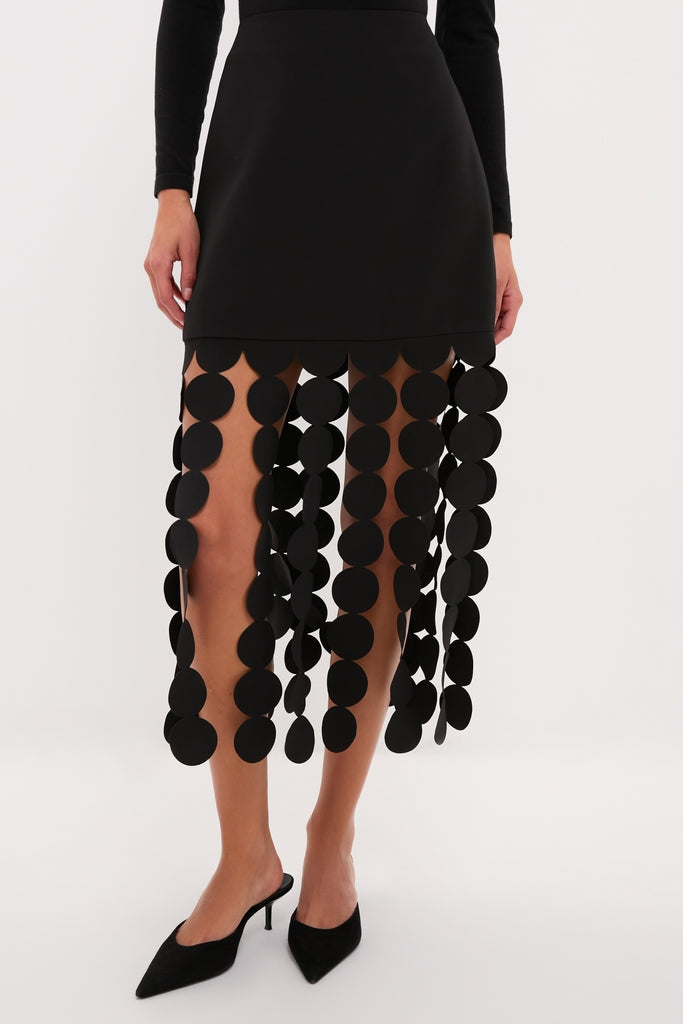 Woman wearing Black Multi Circle Mercedes Maxi Skirt with dangling black discs, paired with pointed-toe black mule heels, exuding a classic and effortless high-end look.