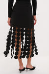 Black Multi Circle Mercedes Maxi Skirt with matte black disc fringe, styled effortlessly with minimalist black mules, exuding classic, high-end fun and graphic movement.
